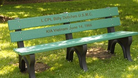 A bench with the name of l cpl billy dutches and date of birth.