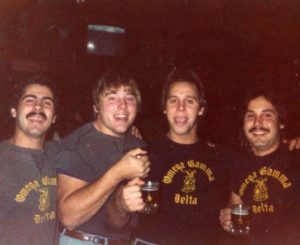 A group of men standing next to each other holding beers.