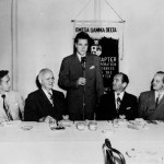 A group of men sitting at a table with microphones.