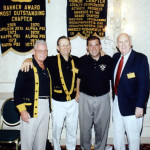 Four men standing in front of a banner.